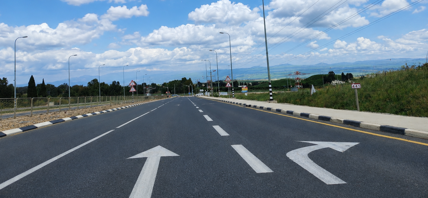 חיצים לבנים מצוירים על כביש אספלט, מסמנים כיווני נסיעה